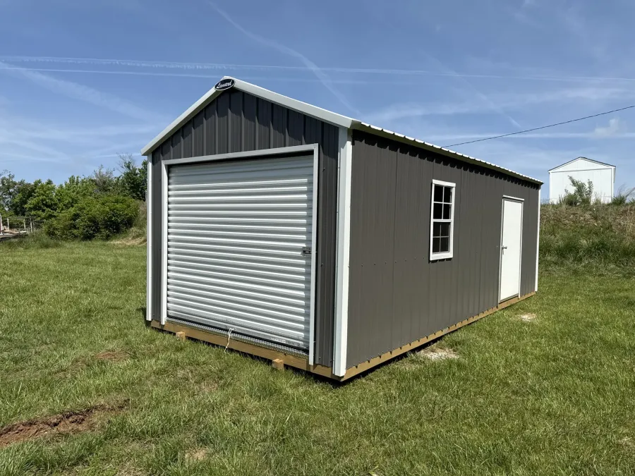12x24 gray metal garage with white trim, a roll-up door, a walk-in door and a window, on grass