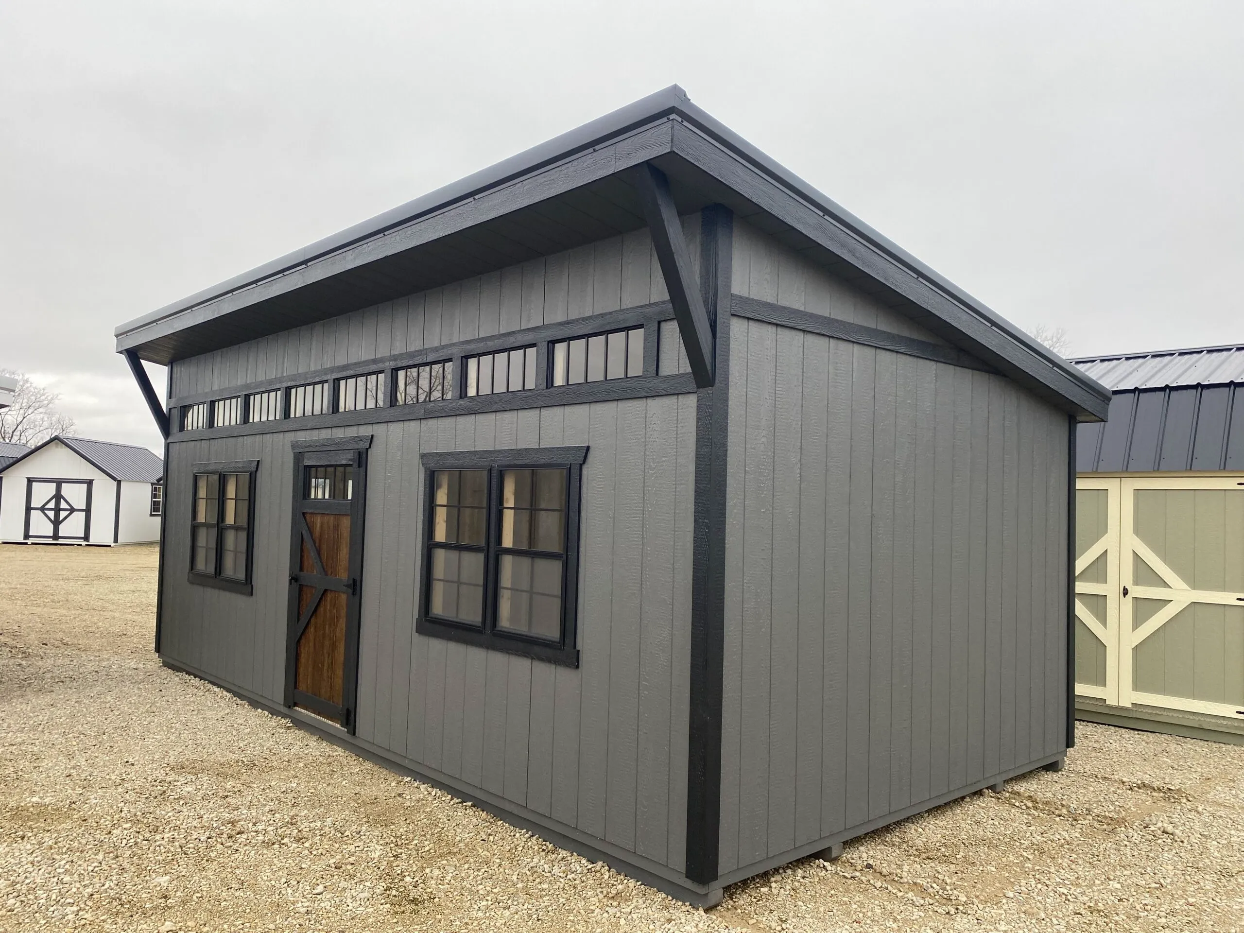 Gray workshop building with higher sidewalls, a row of transom windows and a full entry door