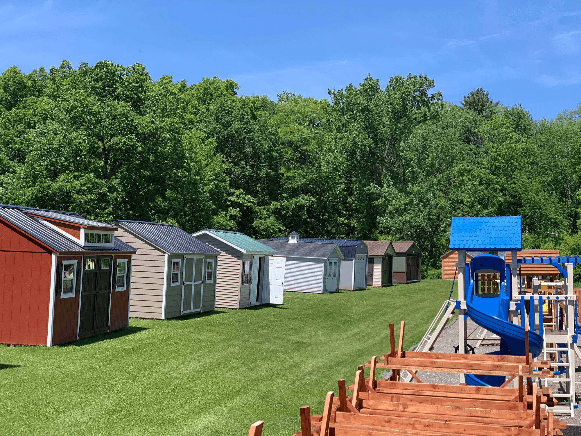 Row of storage buildings beside a wooden playset with a blue canopy