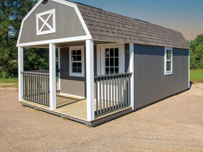 Gray cabin with a covered front porch, white railing and a gambrel roof