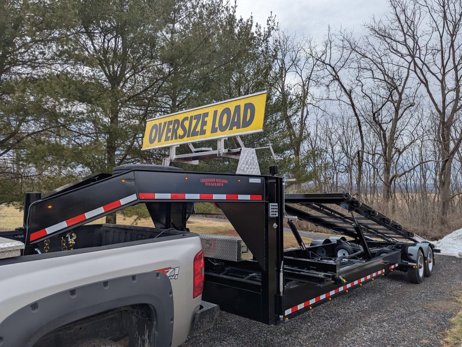 Black Creekside gooseneck shed trailer with an oversize load sign