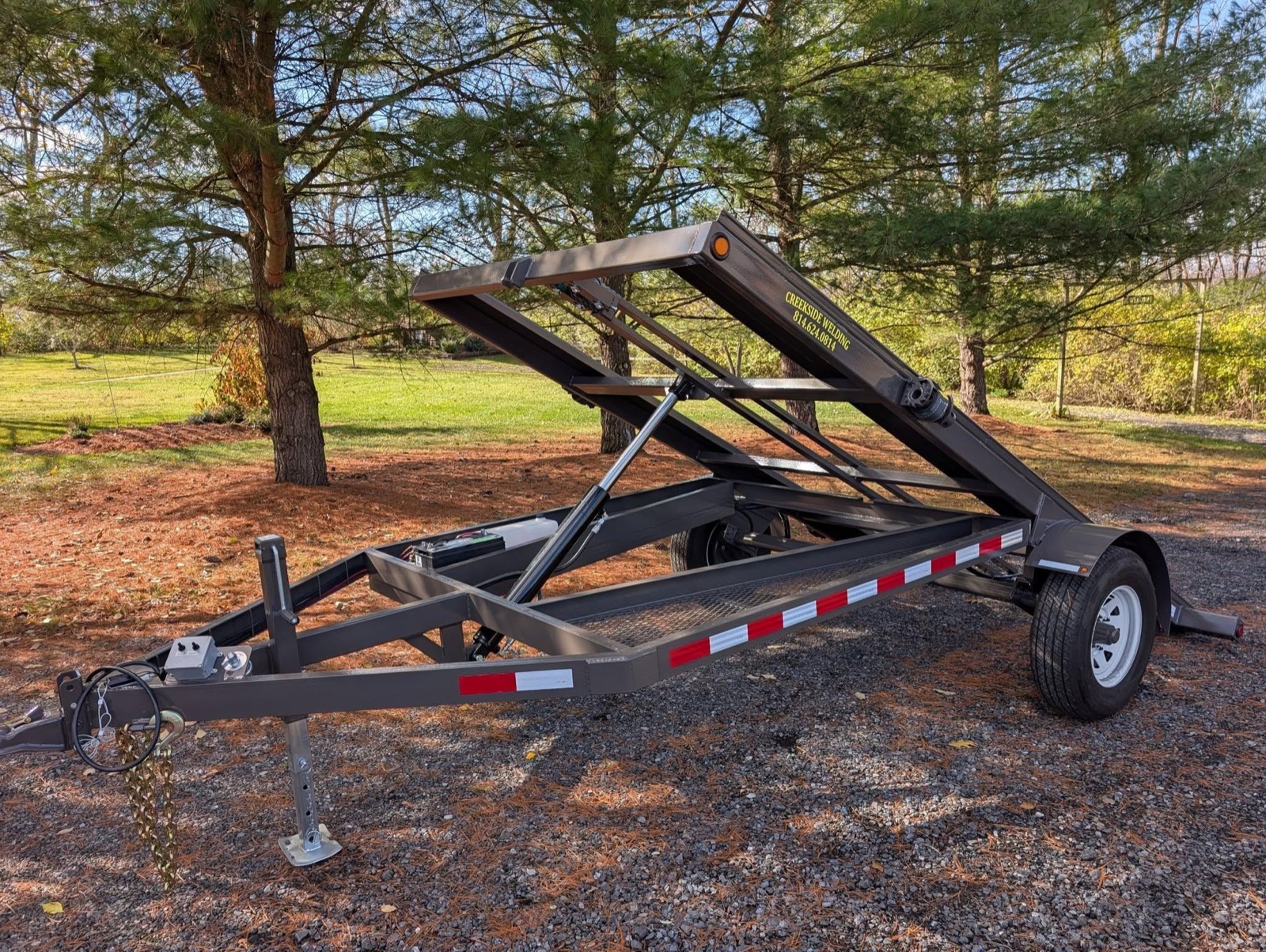 Grey single-axle Creekside shed trailer with the tilt frame raised