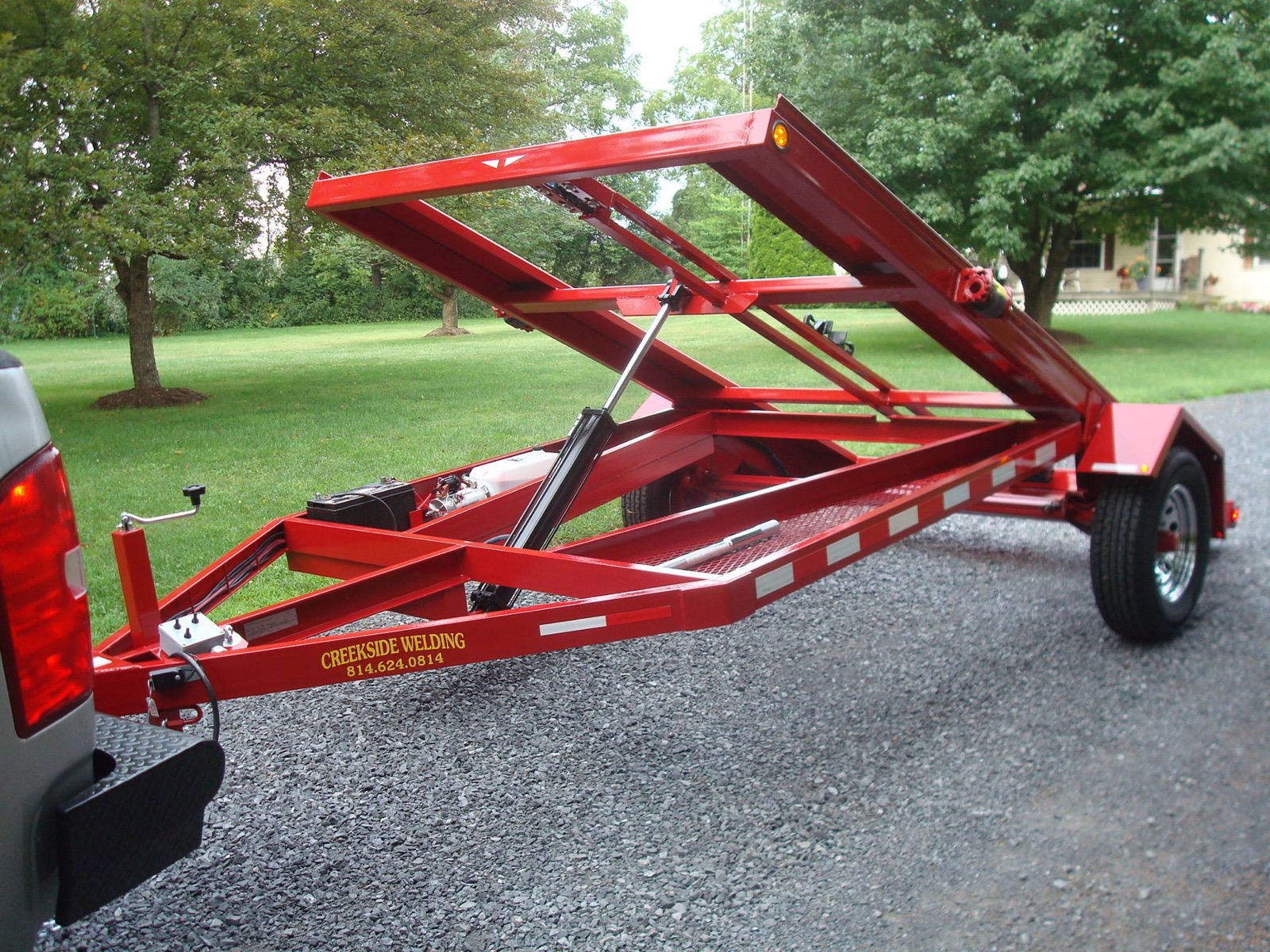 Red Creekside Welding single-axle shed trailer hitched to a truck
