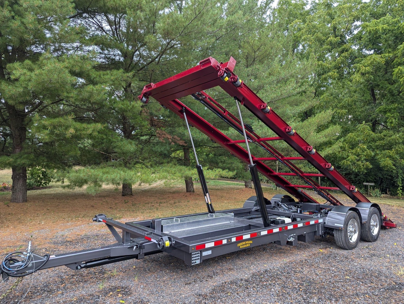 Red Creekside shed trailer with its deck tilted up